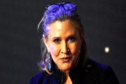 Darkly lit headhsot of the late actress Carrie Fisher who played Princess Leia