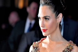 Israeli actress Gal Gadot wearing a sequined coral dress with her hair in a chignon staring off to the side as if on the red carpet