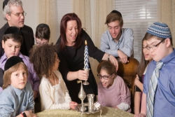 Group of adults and children with disabilities together lighting a twisted Havdalah candle 