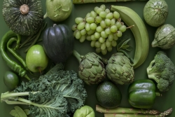 Flatlay of green fruits and vegetables atop a green background