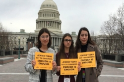 Three teen girls holding signs that says JEWS DEMAND ACTION in front of the US Capitol building