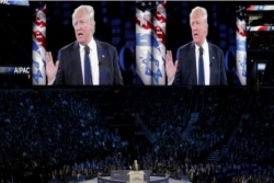 President Trump on stage at the AIPAC Policy Conference with his face shown on large screens about the podium