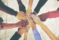 Peoples hands together in a circle as if they are working together or celebrating