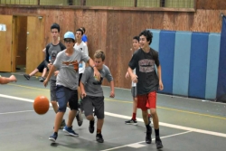 Preteen boys playing basketball on an indoor court 