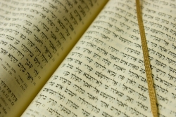 Open book with Hebrew writing and gold page marker across one page