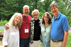 Five smiling individuals including the author and his wife wearing conference name tags and posing outdoors with their arms around one anothers shoulders