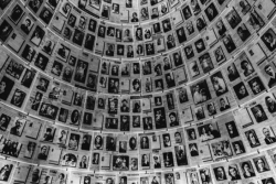 Wall lined with black and white photos of individuals who perished in the Holocaust 