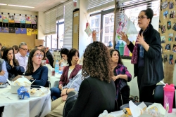 URJ VP of Audacious Hospitality April Baskin stands in a classroom and gestures with her hands as she teaches a room full of participants in the URJ Keshet training partnership