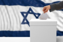 Hand placing ballot in ballot box with Israeli flag in the background