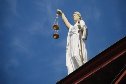 White marble statue of justice holding brass scales 