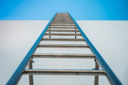 Blue ladder against a white wall leading skyward