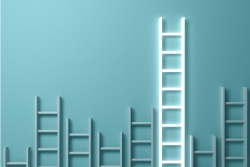 White ladders of all reaches laid against a blue background with the highest ladder glowing as if to represent success
