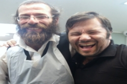 A snapshot of two laughing men one Haredi Jewish with a long beard and the other with close cropped brown hair
