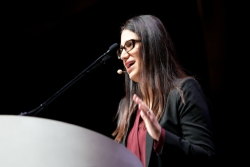 Dr Mona Hanna Attisha at the podium of the URJ Biennial in a pink blouse and black blazer