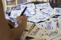 A womans hand writing out sticky name tags with a blue marker