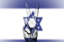 Fingers giving the peace sign in front of an Israeli flag