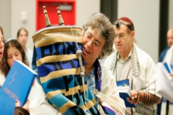 Woman holding the Torah scrolls while other celebrate behind her 