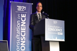 Rabbi Jonah Pesner speaking at a dais at the Consultation of Conscience