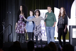 Group of multiracial teens and adults standing on stage in front of a NFTY sign 