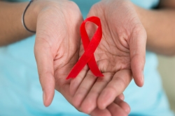 Female hands holding red ribbon for AIDS awareness
