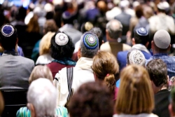 Back view of the heads of worshipers facing forward wearing kippot