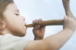 Child blowing the Shofar during the Jewish holiday of Rosh HaShanah