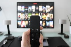 Closeup of someone holding a remote at a TV screen