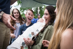 Four smiling, laughing teens passing a Torah scroll from one to the next