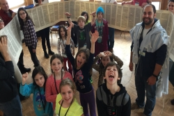 Kids standing around unrolled Torah scroll