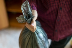 Closeup aerial view of a mans hand holding a black trash bag in a kitchen