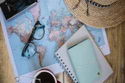 Flatlay of travel items including a map a passport and sunglasses