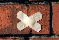 Two crossed Bandaids over a patch of brick wall