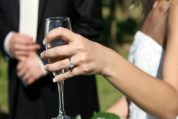 Closeup of a bride holding a glass of champagne with groom in the background behind her