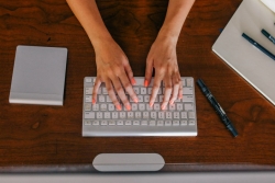 Aerial view of a womans hands on a white keyboard as if typing