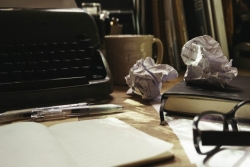 Desktop with typewriter pens crumpled paper and ope notebook