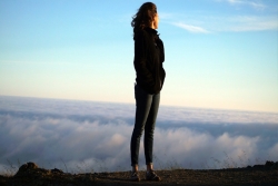 a woman standing at the apex of a mountain
