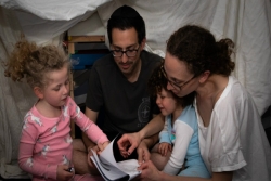 The author with her husband and two children reading a book in the fort they created 