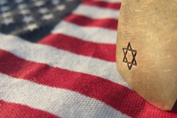 American flag with a stone that has a Star of David on it resting across one corner of the flag