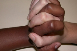 African-American hand and Caucasian fingers clasped together