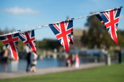 Triangular British bunting/flags in foreground; out-of-focus garden party in background