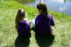 Two girls on the bank of a pond