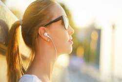 Young woman in profile, wearing sunglasses and earbuds