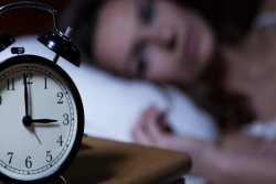 Alarm clock on dresser; woman awake in bed in the middle of the night