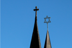 Pointed roofs of a church and a synagogue with a cross atop one and a Star of David atop the other