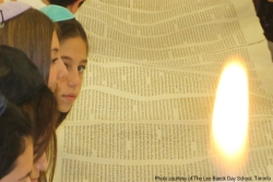 Day school students gathered around unfurled Torah scroll