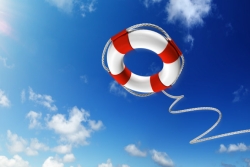 Red and white life preserver with rope against sunny, blue sky with white clouds