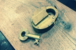 Brass lock and key on wooden background