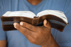 Man holding an open Bible in the palm of his left hand