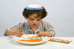 Jewish boy at Passover or Pesach Seder eating Matzah Balls