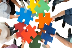 Group of people each holding an oversized puzzle piece of a different color